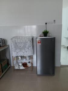 Cette chambre comprend un petit réfrigérateur et une chaise. dans l'établissement Che Ta Homestay for musliim only, à Kampong Geliga Besar
