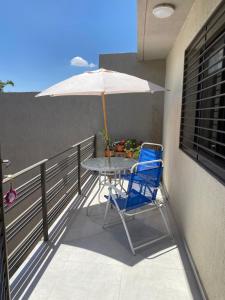una mesa y una silla con una sombrilla en el balcón en Departamento Alberdi - Cochera privada y techada en Godoy Cruz