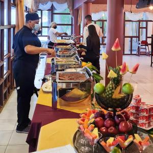 a group of people standing at a buffet line with food at Hotel Partenon Beach in La Ceiba