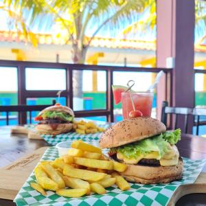 a hamburger and french fries on a table with a drink at Hotel Partenon Beach in La Ceiba