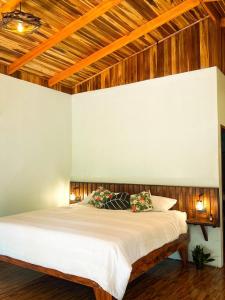 een slaapkamer met een groot wit bed en houten plafonds bij Ficus house in Boca Tapada
