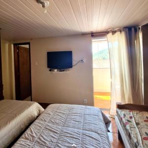 a bedroom with a bed and a tv on the wall at Hospedagem Doce Lar - Casa Azaleia in Teresópolis +12 photos