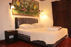 a bedroom with a bed with a painting on the wall at Kebun Rohani Cottages in Senggigi