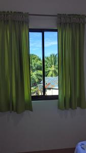 a window with green curtains in a bedroom at Charlina Inn Panglao in Panglao Island