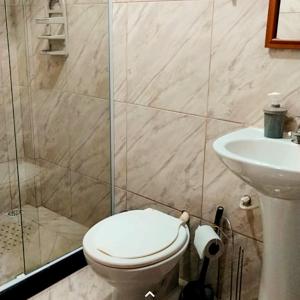 a bathroom with a toilet and a shower and a sink at Hospedagem Doce Lar - Casa Girassol in Teresópolis