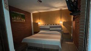 ein kleines Schlafzimmer mit einem Bett in einer Ziegelwand in der Unterkunft Posada Verona in Huasca de Ocampo