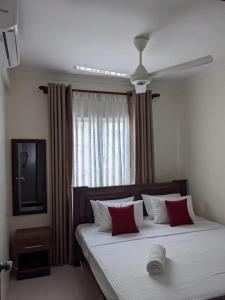 a bedroom with a bed with red pillows and a window at Richmond Hill SHA Residencies in Galle