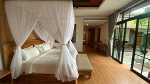 1 dormitorio con cama con dosel y mosquiteras blancas en Sawitri Anandhita Luxury Villas, en Ubud