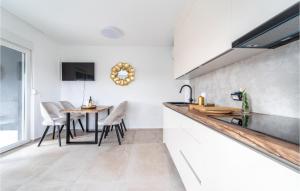 una cucina con pareti bianche, tavolo e sedie di Lovely Apartment In Sukosan With Wifi a Sukošan (San Cassiano)