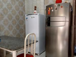 a kitchen with a refrigerator and a table and a chair at Quarto bem próximo ao Pelourinho in Salvador
