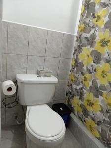 a bathroom with a toilet and a flower shower curtain at Casa de los Pilinchos in San Lorenzo El Cubo