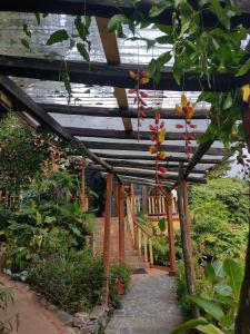 un jardín con pérgola de madera y flores rojas en Hotel Claro de Luna, en Monteverde