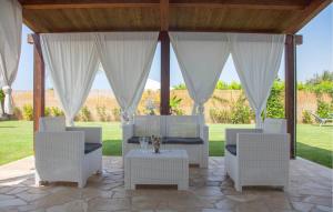une terrasse couverte avec des chaises blanches et une table. dans l'établissement Nice Home In Scicli With Swimming Pool, à Scicli