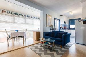 een woonkamer met een blauwe bank en een tafel bij BEACH Living - “A bit of Mykonos near Mordialloc!” in Aspendale