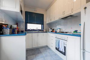 een keuken met witte kasten en blauwe aanrechtbladen bij BEACH Living - “A bit of Mykonos near Mordialloc!” in Aspendale