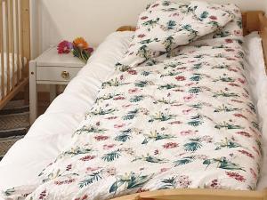 a bed with a white blanket with flowers on it at Holiday home Nordfold in Nordfold