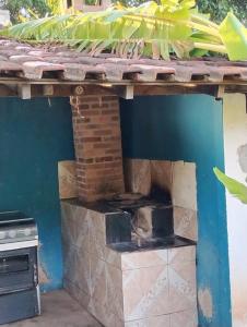 an outdoor kitchen with a brick oven and a blue wall at Sítio com piscina e lago para pescaria in Itaboraí