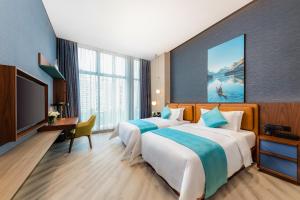 two beds in a hotel room with a television at Sha Zhi Ye Serviced Apartment Hotel - Houjie Wanda Plaza Liaoxia Subway Station in Dongguan