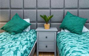 two beds with green pillows and a night stand with a plant at Beautiful Home In Ryn With Sauna in Ryn