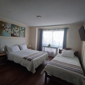 two beds in a hotel room with a window at Hotel 251 in Viña del Mar