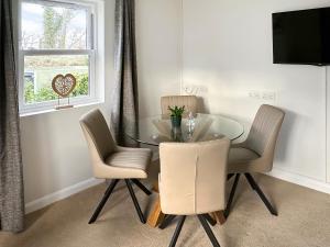 a glass dining room table with two chairs and a window at Derwent Cottage in Keswick