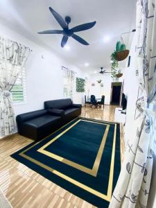 - un salon avec un canapé noir et un ventilateur de plafond dans l'établissement Umbai Village Melaka homestay, à Merlimau