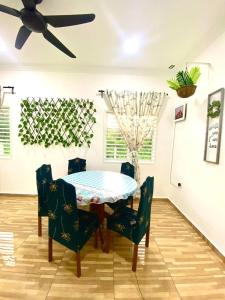 - une table à manger avec des chaises et un ventilateur de plafond dans l'établissement Umbai Village Melaka homestay, à Merlimau