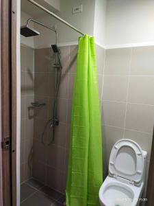 a bathroom with a green shower curtain and a toilet at G&M Comfy place for your stay at SMDC Coast Residences in Manila