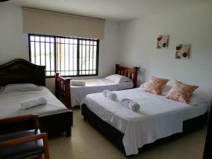 1 dormitorio con 2 camas y 2 ventanas en Campos de Bethel - Casa campestre en Rivera