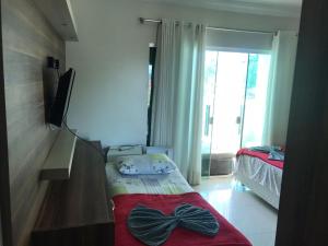 1 dormitorio con 1 cama, TV y ventana en Pousada Ilha do Itacolomi, en Penha