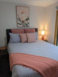 Schlafzimmer mit einem Bett mit rosa und blauen Kissen in der Unterkunft Buninyong Country Cottage in Buninyong