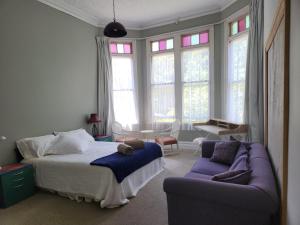 a bedroom with a bed and a couch and windows at Quirky Villa in Whanganui