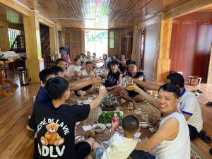 Eine Gruppe von Menschen, die an einem Tisch sitzen und Essen essen. in der Unterkunft Sakura Homestay in Sa Pa