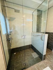 a shower with a glass door in a bathroom at Single room with window near metro in Dubai