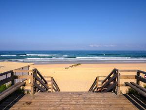 eine hölzerne Promenade, die zu einem Strand mit dem Meer führt in der Unterkunft Chalet cosy pour 4 pers à Mimizan, proche plages et pistes cyclables, classé 2 étoiles - FR-1-50-108 in Mimizan + 4 Fotos