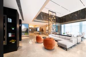 a living room with a white couch and orange chairs at Sha Zhi Ye Serviced Apartment Hotel - Houjie Wanda Plaza Liaoxia Subway Station in Dongguan