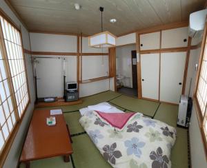 a room with a bed and a table in it at Sunshine Kyohei in Nozawa Onsen