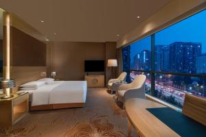 um quarto de hotel com uma cama e uma grande janela em Renaissance Chengdu Hotel em Chengdu