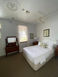 a bedroom with a white bed and a ceiling fan at Seaview House in Queenscliff