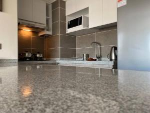 a kitchen with white cabinets and a granite counter top at Hermoso Departamento con excelente vista, a pasos de la Quinta Vergara, cercano a Reloj de Flores y Playa Caleta Abarca in Viña del Mar