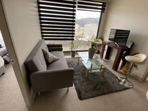 a living room with a couch and a piano at Hermoso Departamento con excelente vista, a pasos de la Quinta Vergara, cercano a Reloj de Flores y Playa Caleta Abarca in Viña del Mar