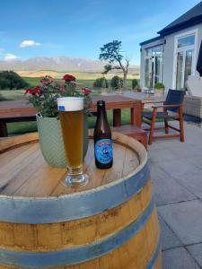 a bottle of beer and a glass on a barrel at Number 74 on Lockhart in Oturehua