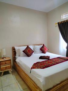 a bedroom with a white bed with red pillows at Dika Accommodation Ubud in Ubud