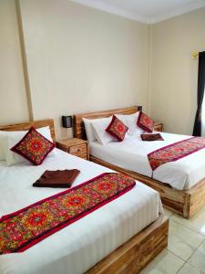a room with two beds with red pillows on them at Dika Accommodation Ubud in Ubud