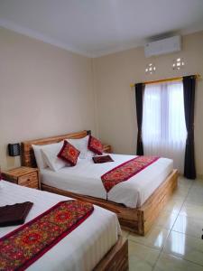 a hotel room with two beds and a window at Dika Accommodation Ubud in Ubud