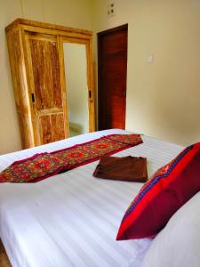 a bedroom with a large white bed with red pillows at Dika Accommodation Ubud in Ubud