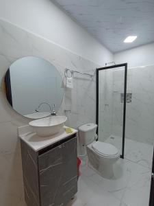 een badkamer met een wastafel, een toilet en een spiegel bij HOSPEDAJE EL ENSUEÑO in Doradal