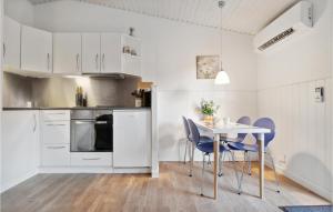 a kitchen with white cabinets and a table and chairs at Cozy Apartment In Nex With Kitchen in Neksø
