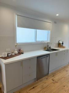 a kitchen with white cabinets and a sink and a window at Owl+Oak in Castlemaine