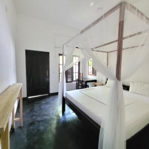 - une chambre avec un grand lit blanc à baldaquin dans l'établissement Agra Arugambay, à Baie d'Arugam